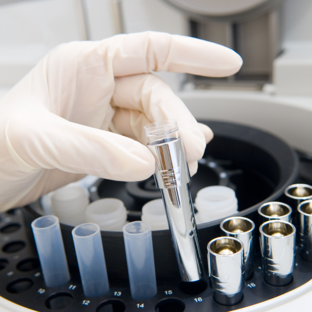 Test tubes with a gloved hand showing the kind of work that takes place at BAS